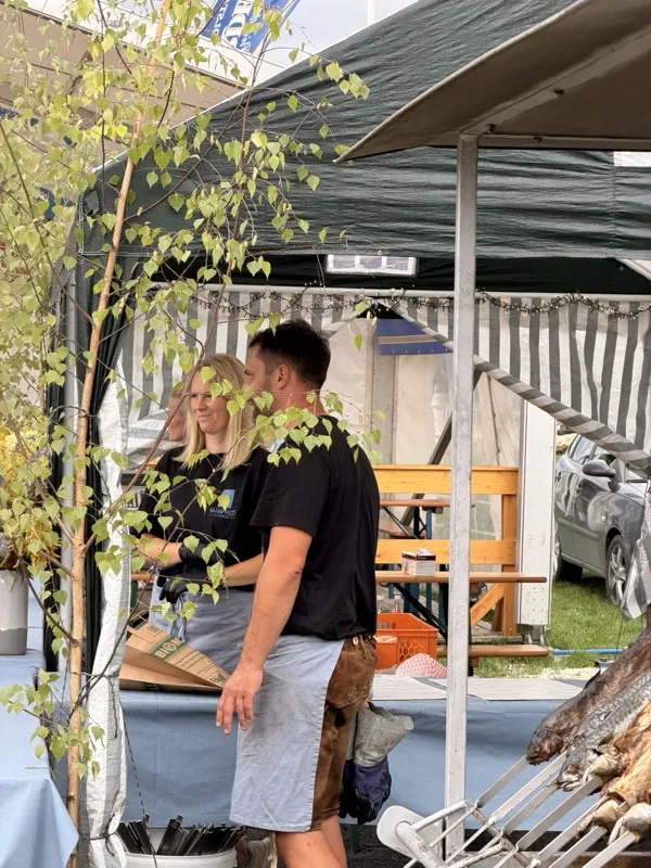 Zwei Mitarbeitende in Firmenshirts am Grill des Standes